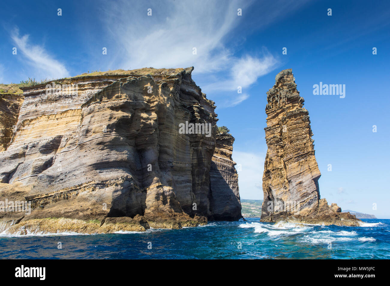 layered basalt rock formations of islet Stock Photo