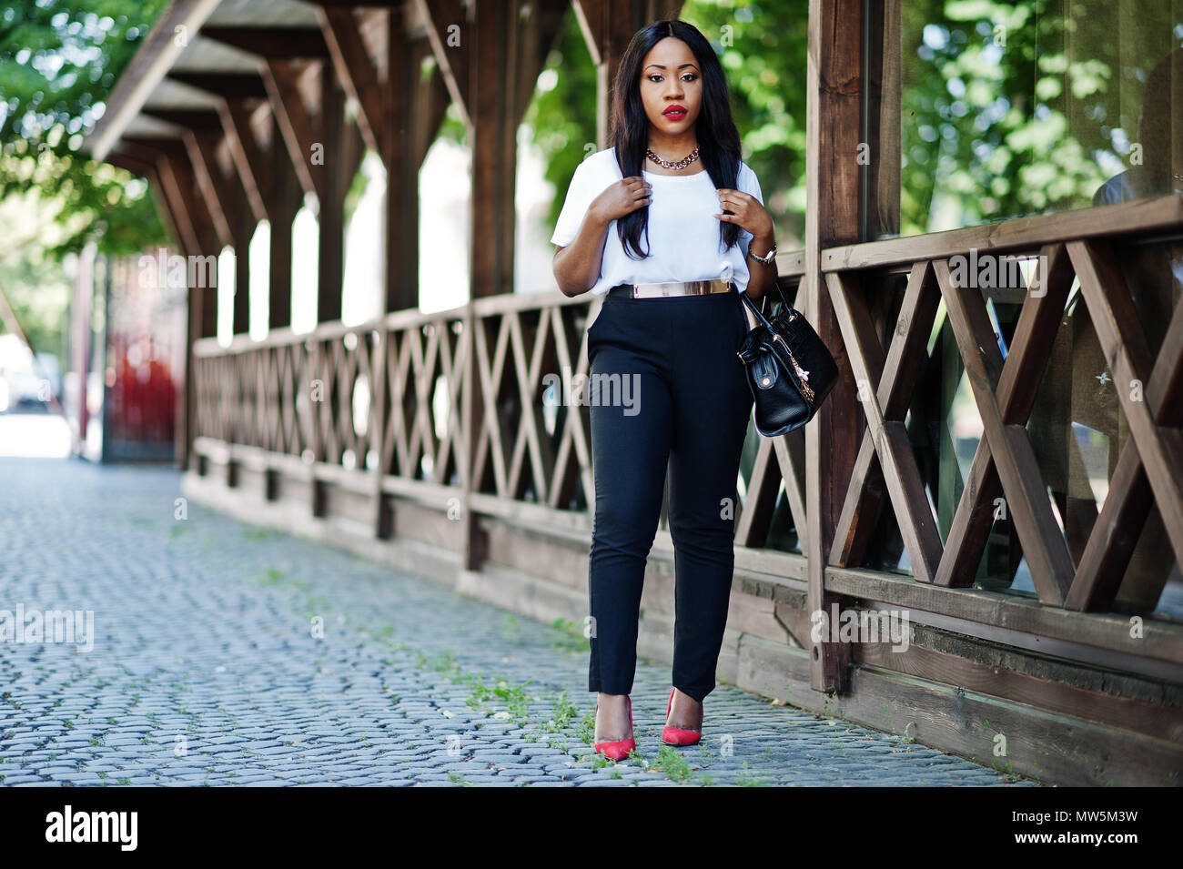 Stylish african american business woman with handbag on streets of city ...