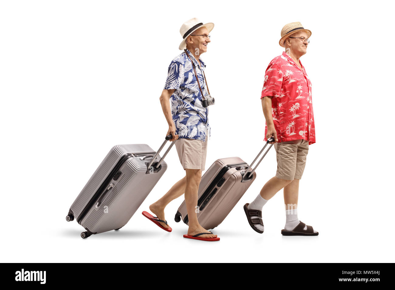 Full length profile shot of two elderly tourists with suitcases walking isolated on white background Stock Photo