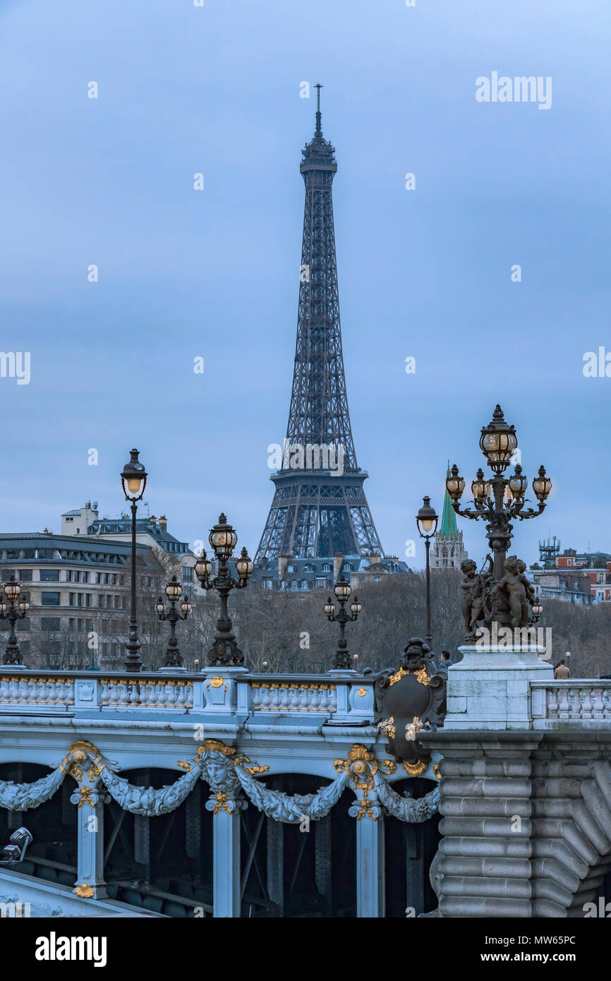 Illuminated lamps at twilight on the Pont Alexandre III bridge with  The Eiffel Tower in the distance ,Paris , France Stock Photo
