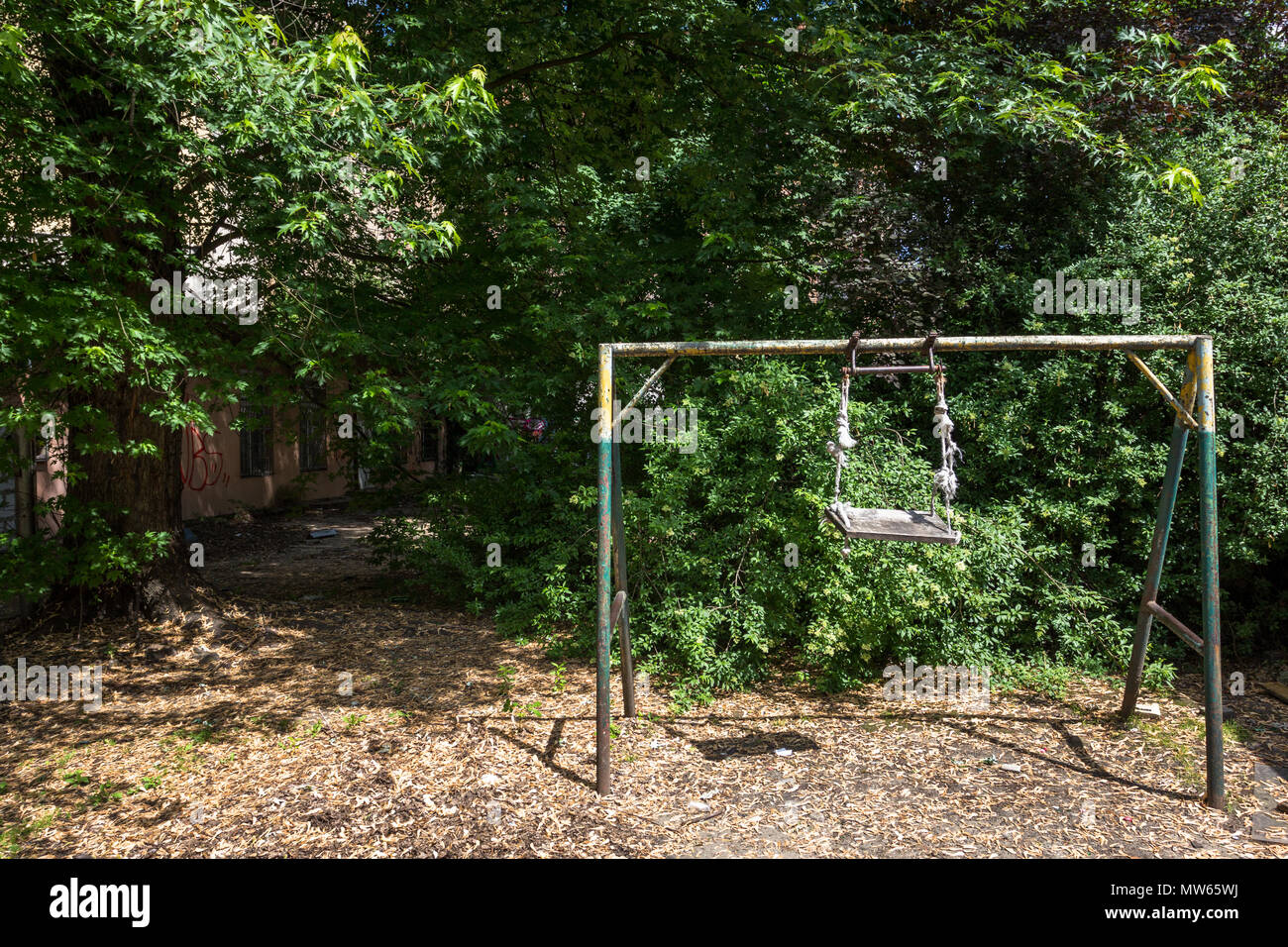 Abandoned derelict courtyard with children's swing with frayed rope. in Lodz, Poland. Stock Photo