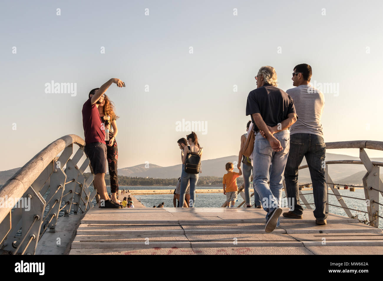 Volos, Thessaly, Greece - May 27th, 2018: People walking and taking photos on a little bridge at the Port of Volos, Pagasetic Gulf. Stock Photo
