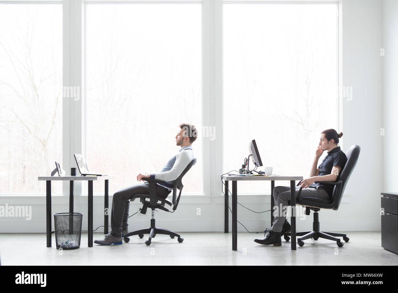 Office workers looking bored and unmotivated in a modern office space. Stock Photo