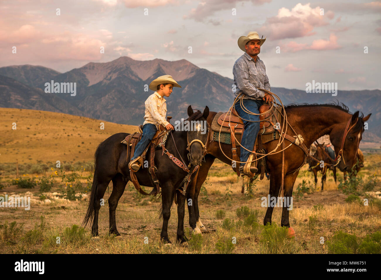 A cowboy and his son ride horses at the foot of the Wasatch Mountains of Utah. Stock Photo