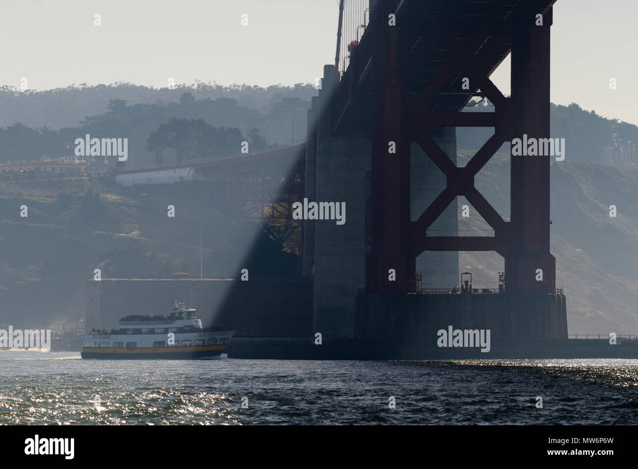 Public water ferry travels under the Golden Gate Bridge as seen from water level Stock Photo