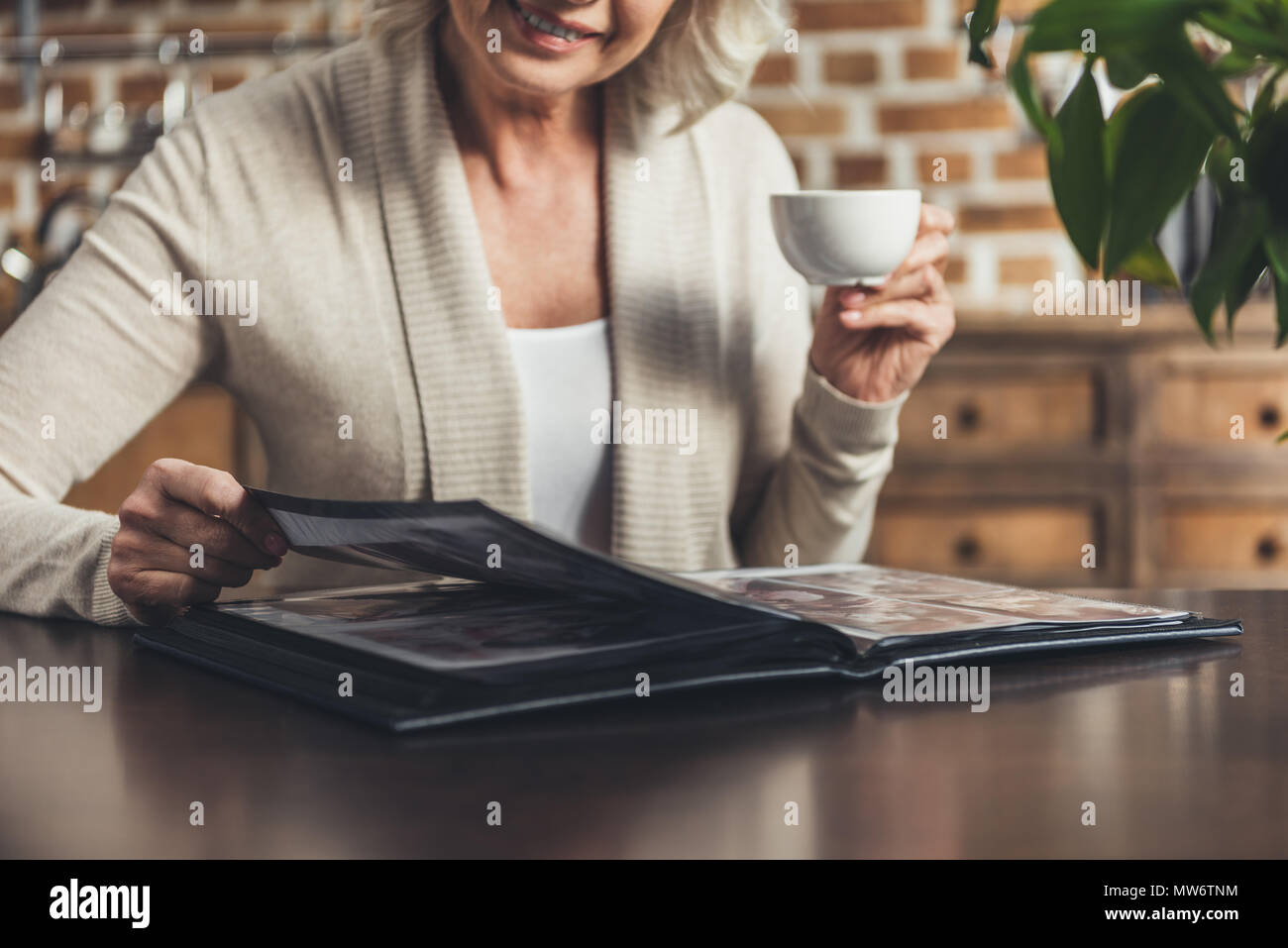 Portrait of senior woman sitting at kitchen table and looking at photo ...