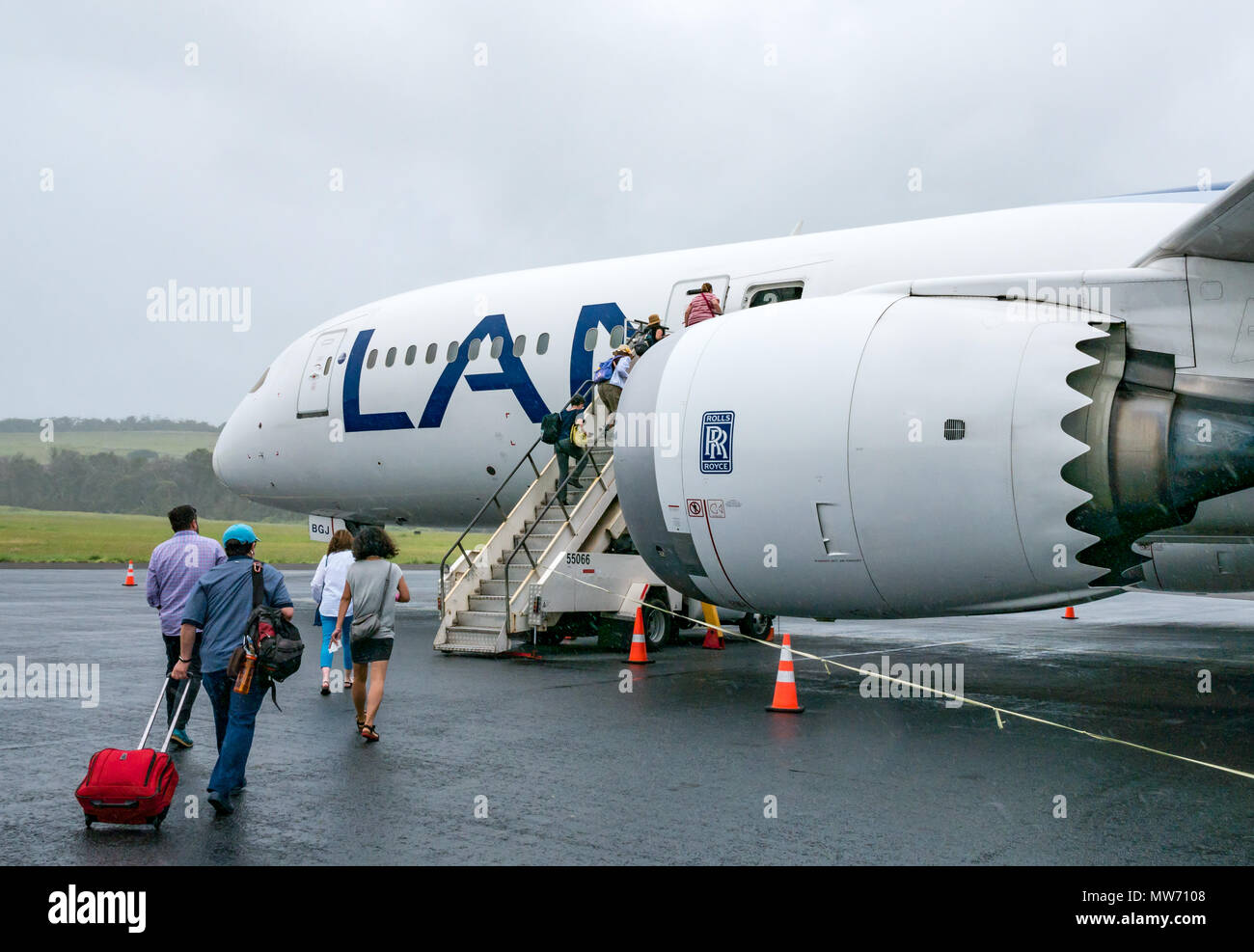 Passengers boarding LATAM airline Dreamliner Boeing 787, during wet weather at Mataveri International Airport runway, Easter Island, Chile Stock Photo