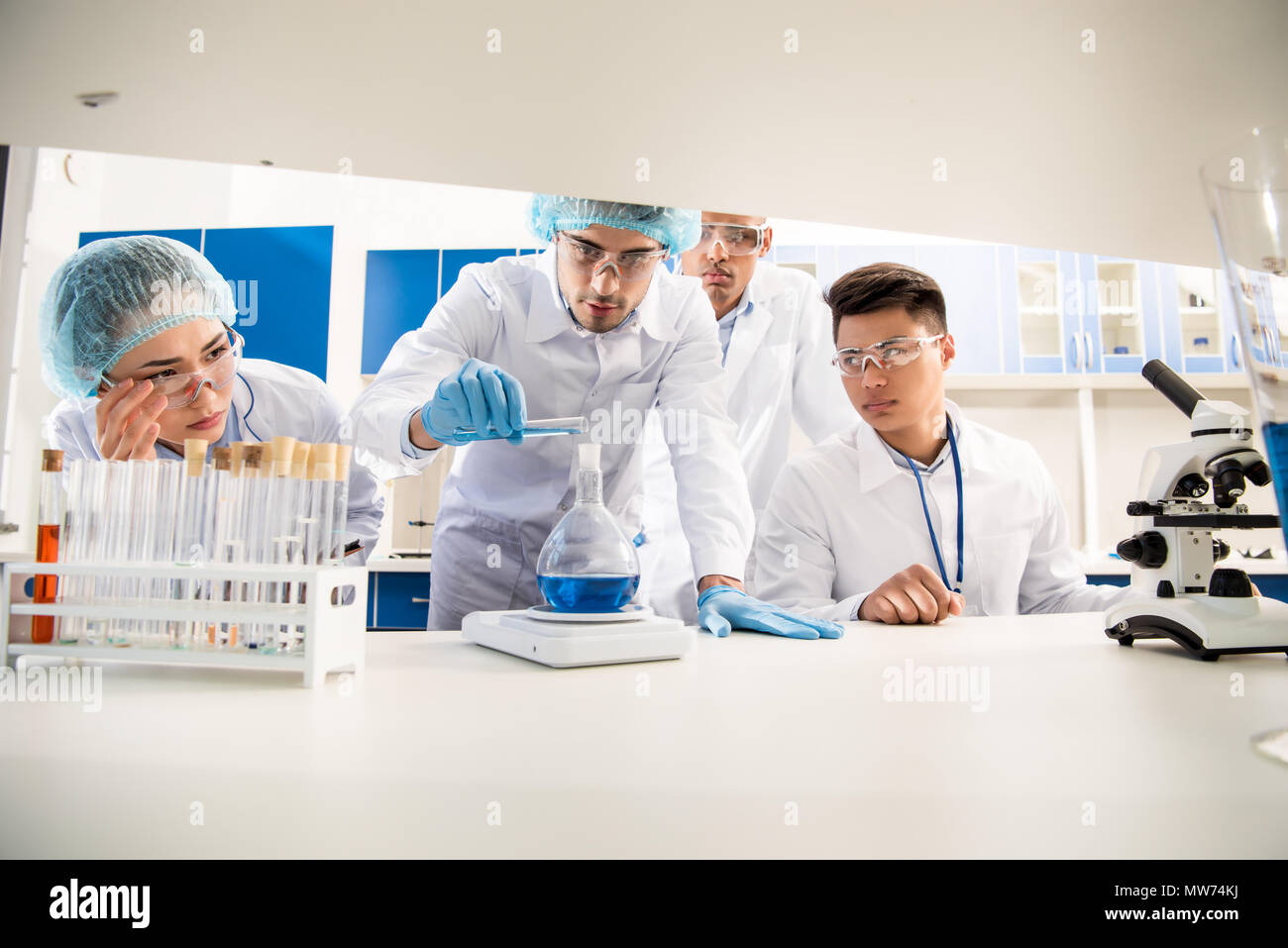 group of medical workers weighing a flask with reagent in laboratory
