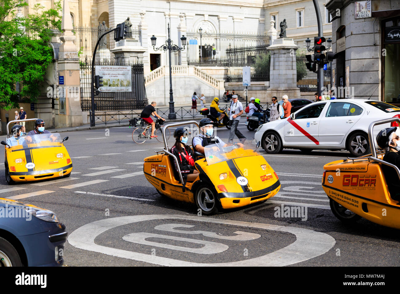 3 wheeled Gocars carrying Chinese tourists wearing smog masks on a tour of Madrid, Spain. May 2018 Stock Photo