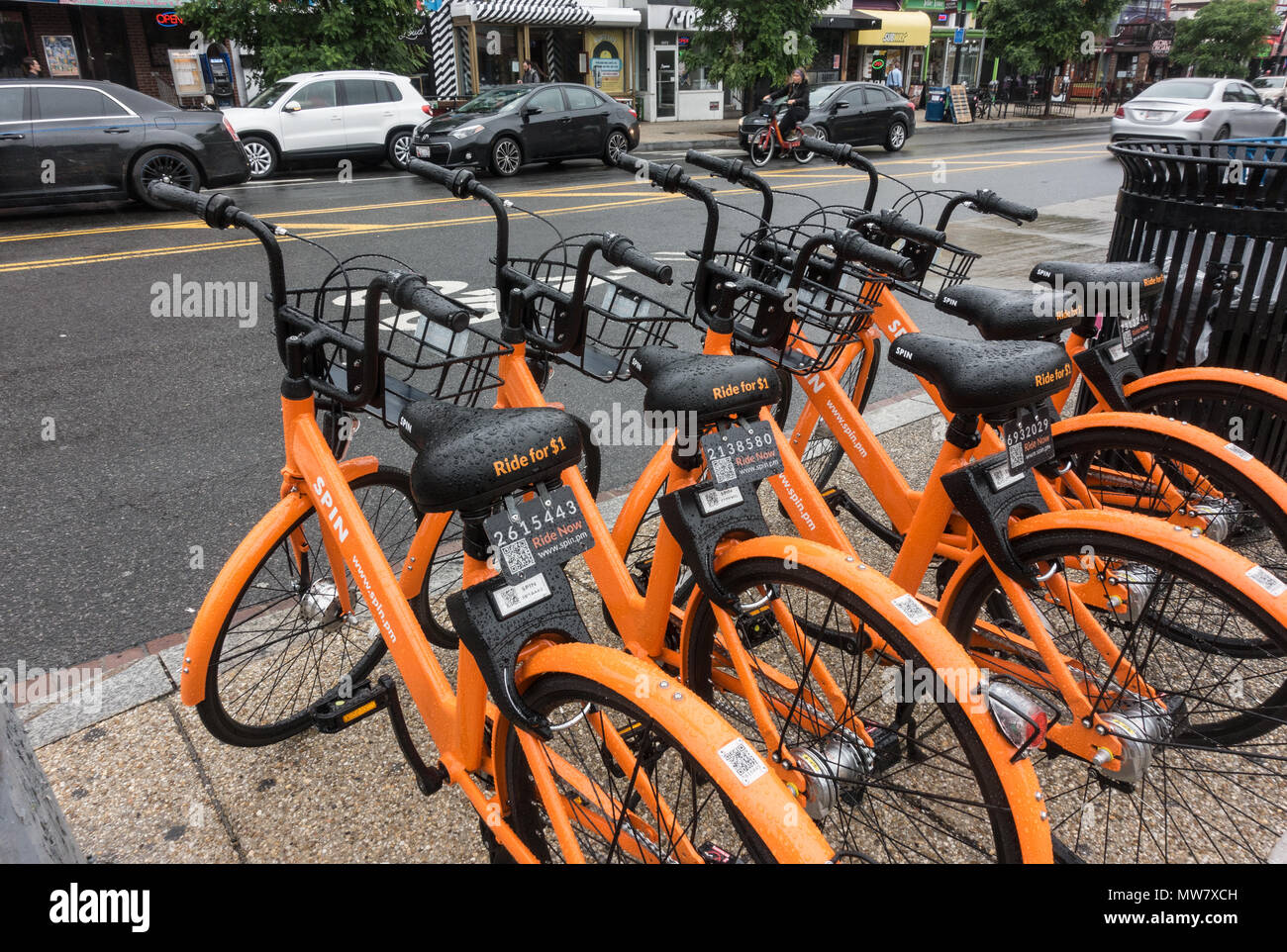 Dockless SPIN bikes await riders on rainy day in Adams Morgan, Wash., DC.  SPIN is one of several dockless bikes on streets during 2018 trial period. Stock Photo