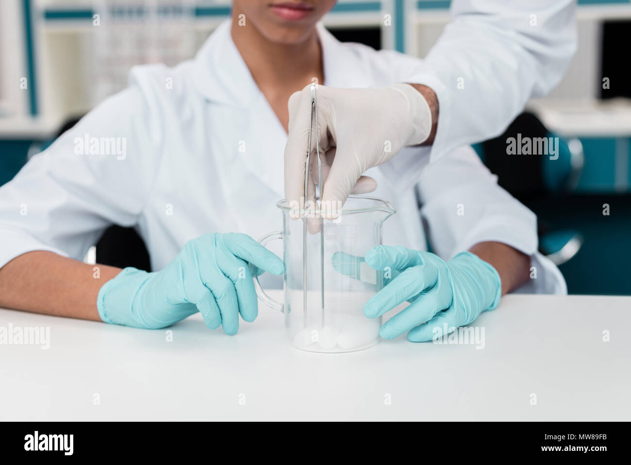 Cropped shot of colleagues in white coats working with reagent in ...