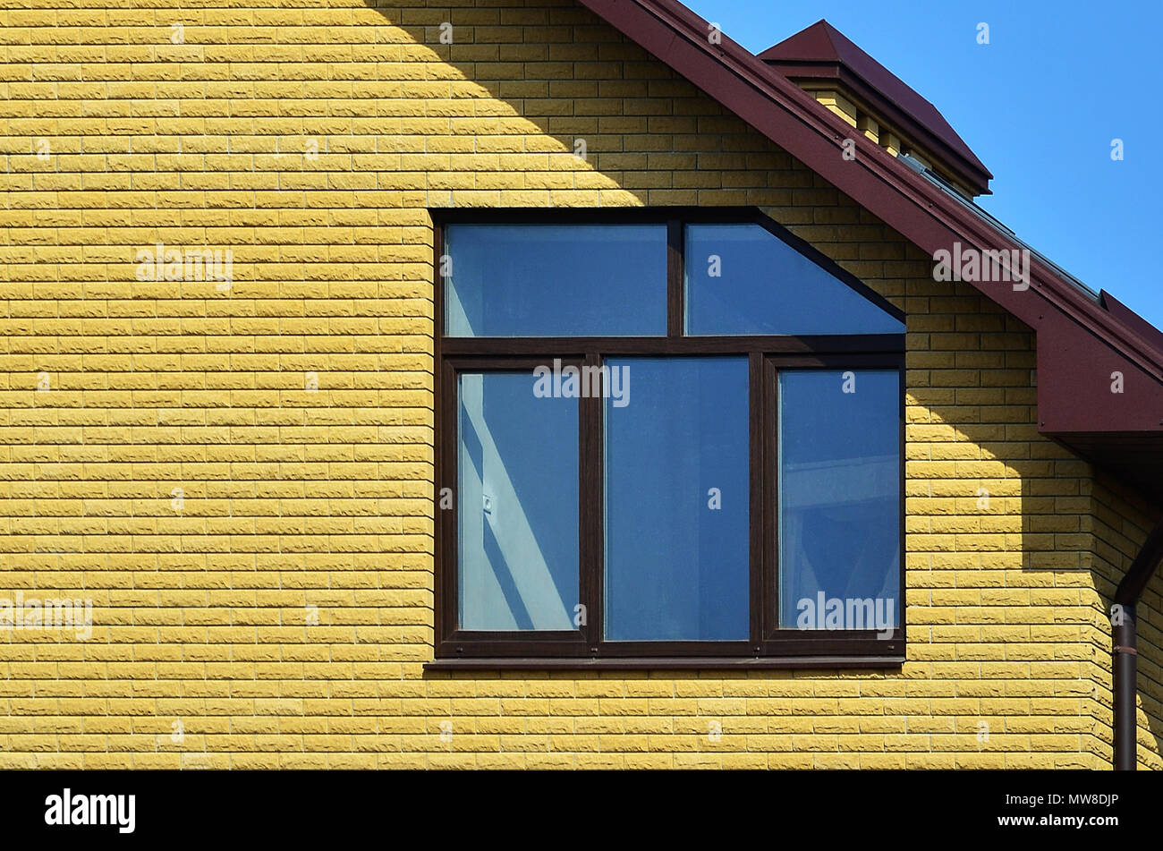 The top of a residential building of yellow brick with a brown roof and ...