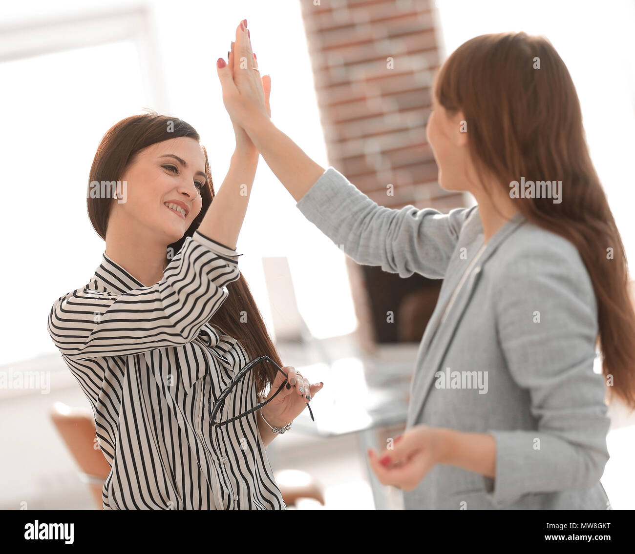 two young co-workers giving each other a high five Stock Photo - Alamy