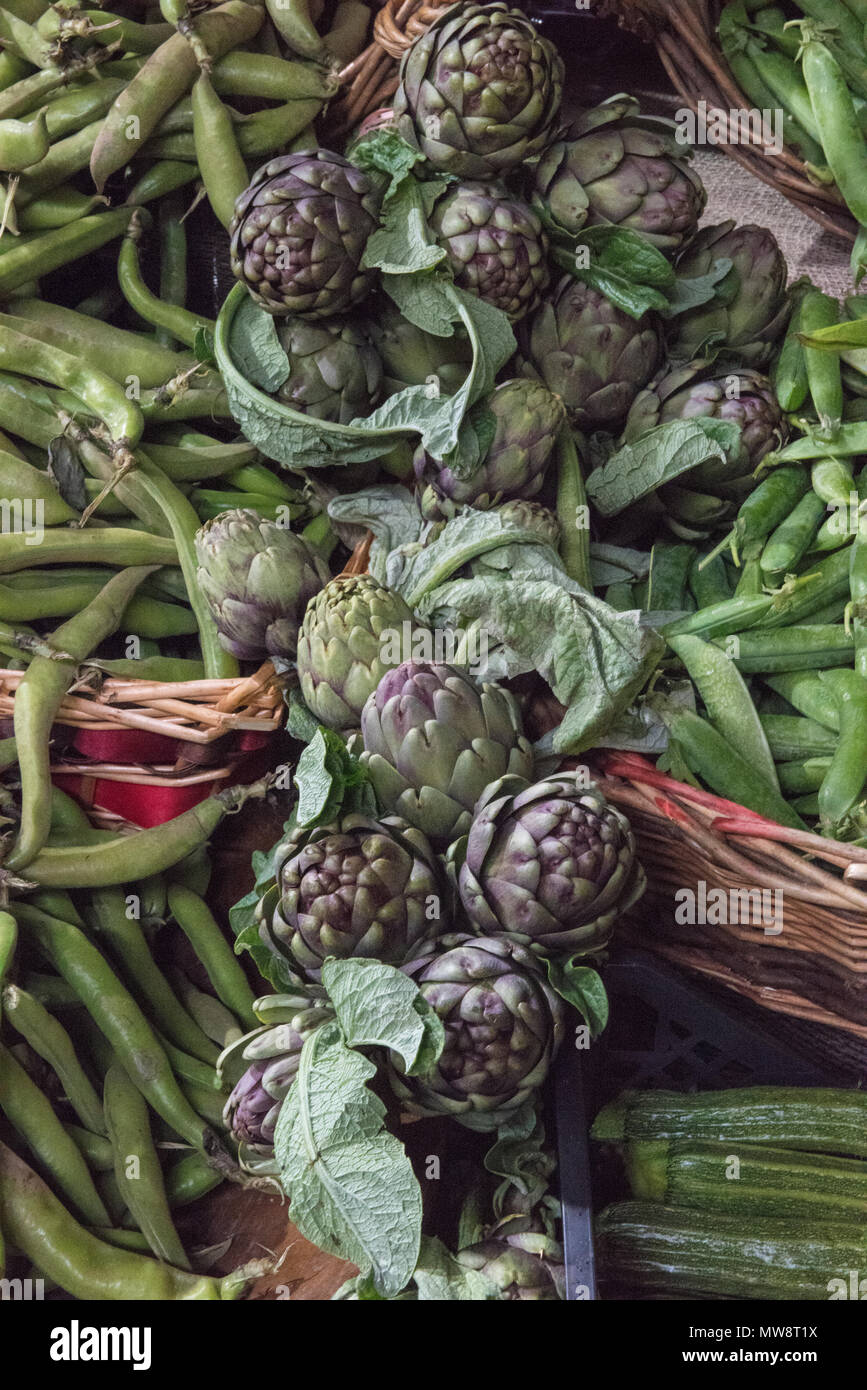 artichokes, broad beans, peas and courgettes on sale at borough market in london. a colourful display of green vegetables fresh cut from the farmland. Stock Photo