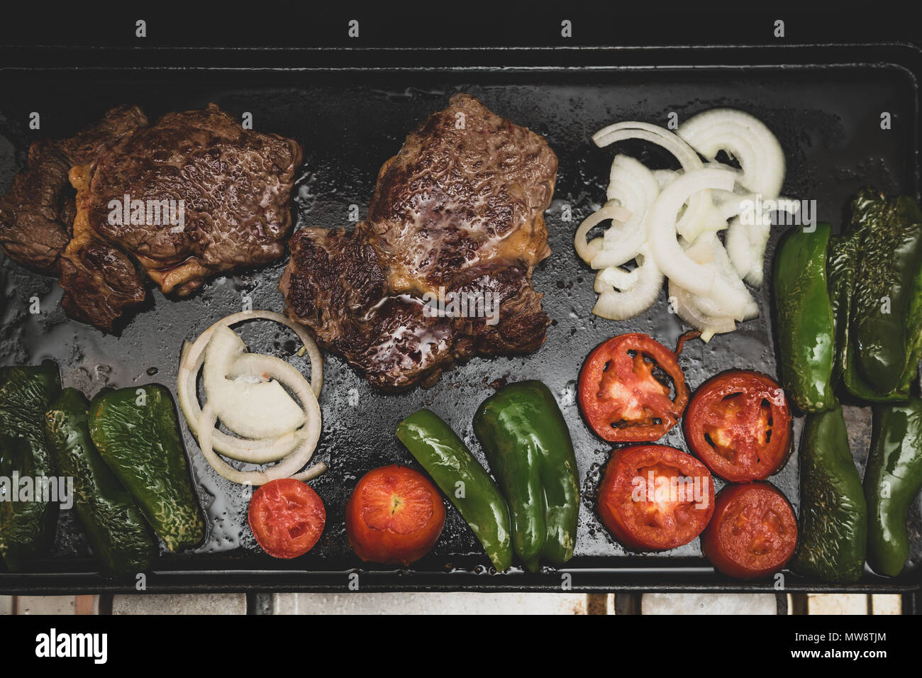 Rib Eye Steak Spanish Bife Ancho Onions Tomatoes And Green Peppers Grilled On Rectangular Cast Iron Flat Griddle Pan Vintage Toned Flat Lay Stock Photo Alamy