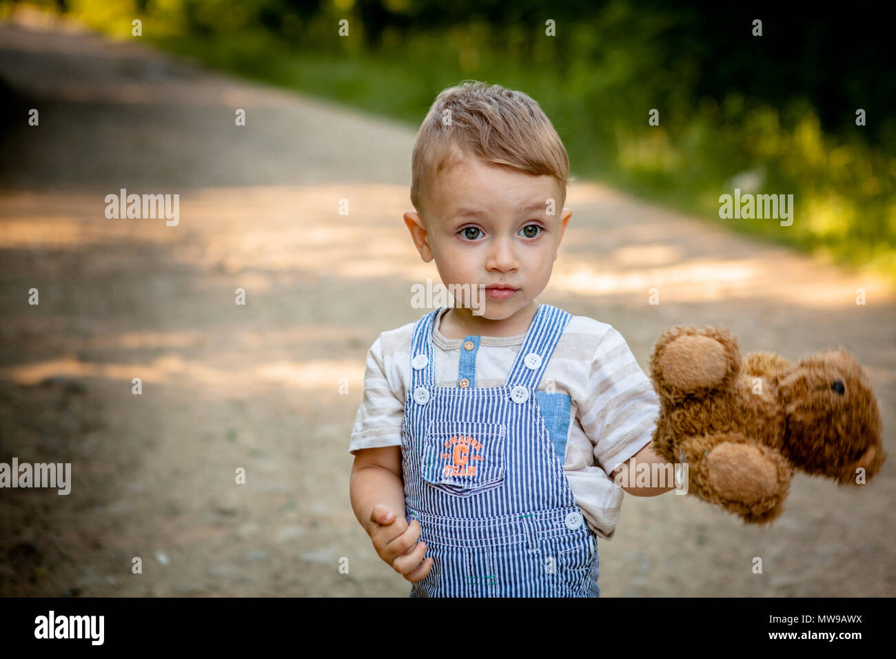Little boy playing with teddy bear on the footpath Stock Photo - Alamy