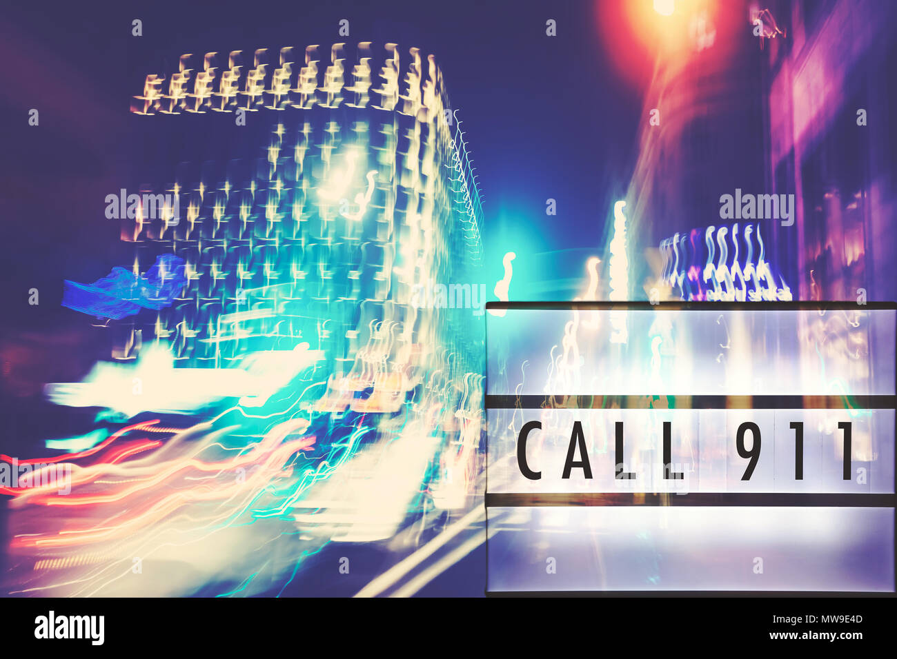 Call 911 text in a lightbox, motion blurred city lights in background, color toned picture. Stock Photo