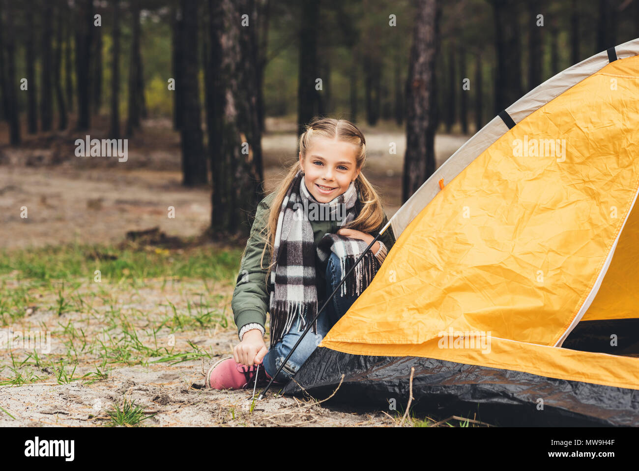 little girl installing camping tent and looking at camera Stock Photo