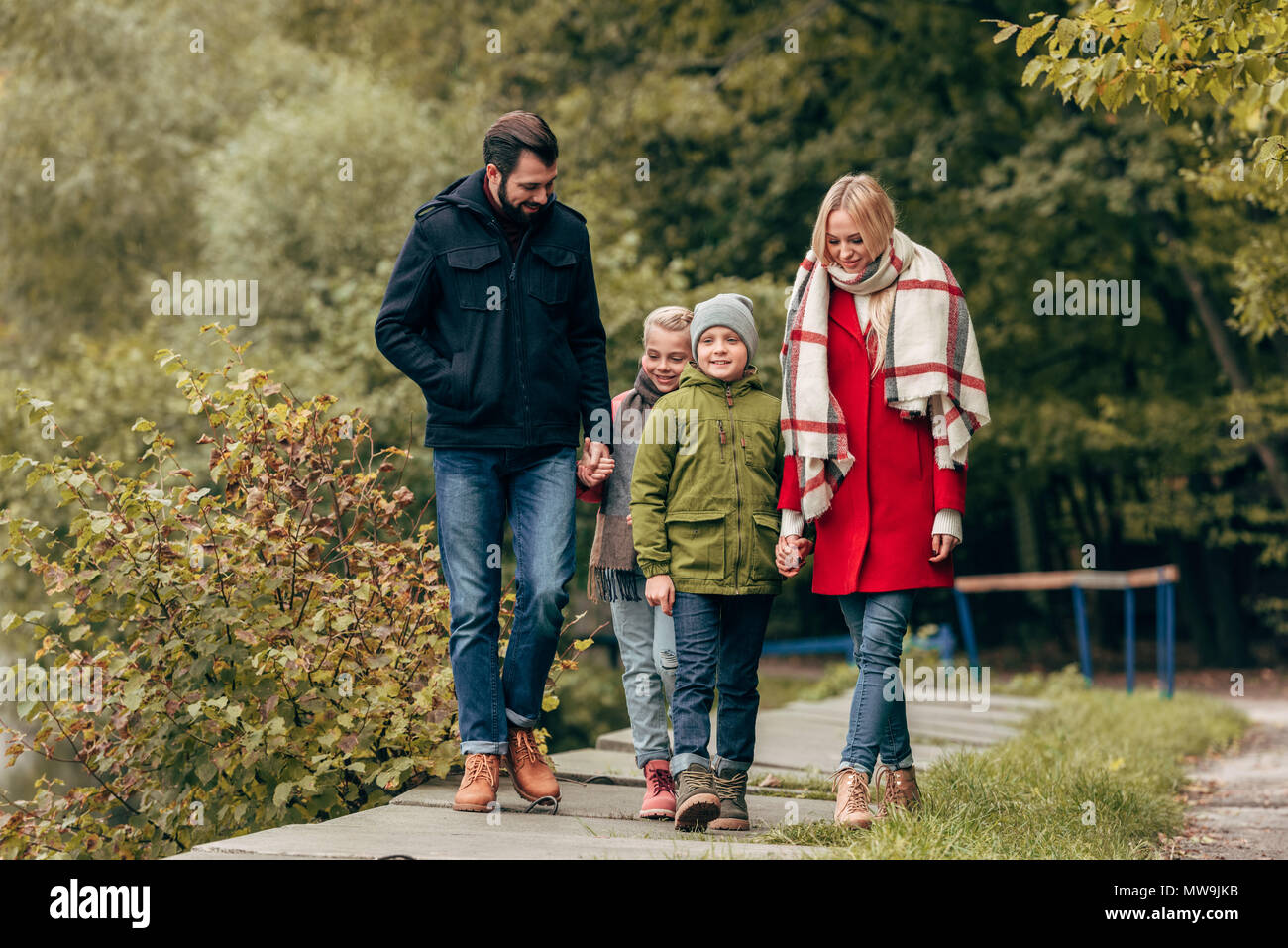 happy young family holding hands and walking in autumn park Stock Photo