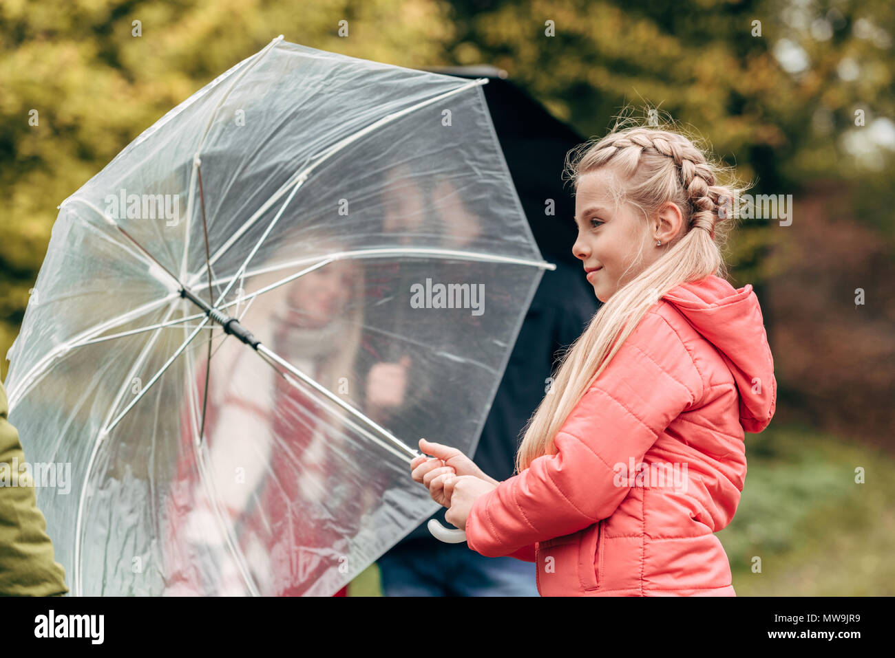 adorable little daughter holding umbrella while parents standing behind Stock Photo