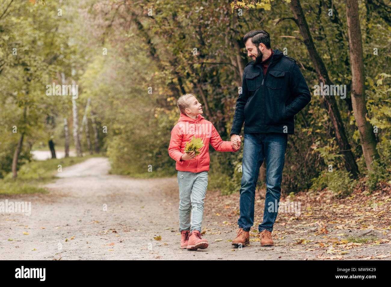 happy father and daughter holding hands and walking together in park ...
