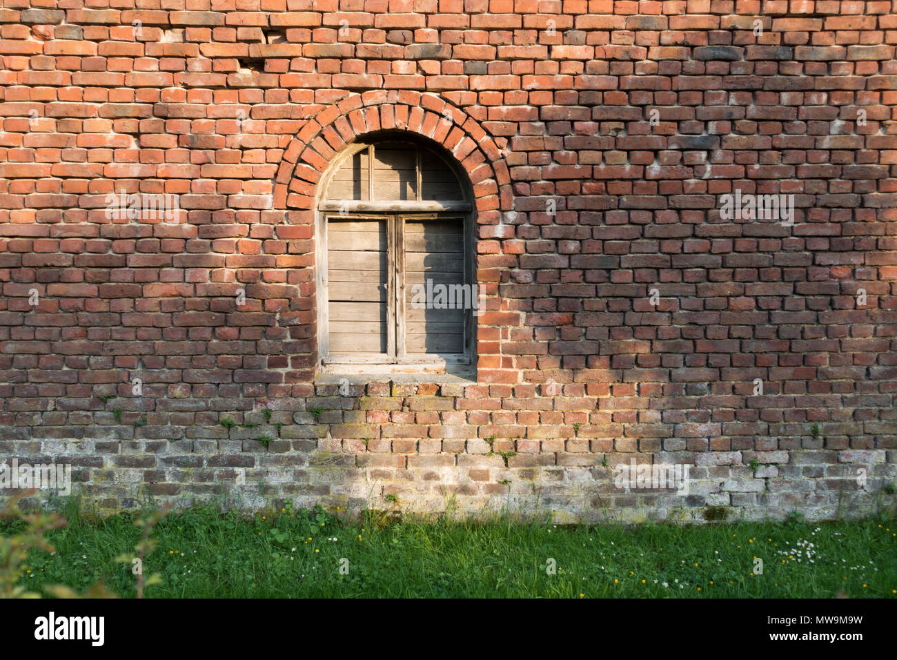 Old wooden arched window, shut down, red bricks vintage wall, farmhouse, Europe Stock Photo