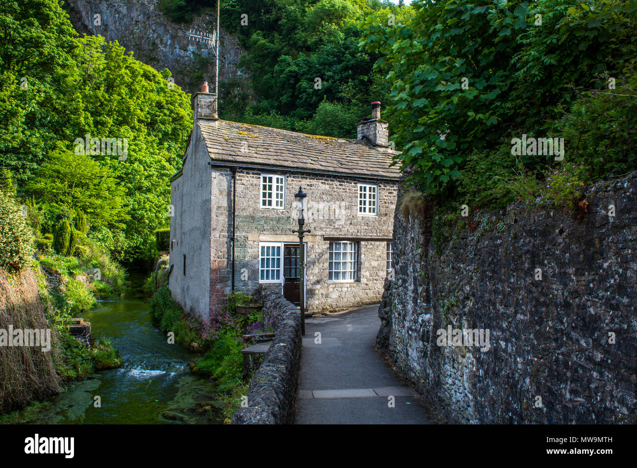 Old cottage by a stream in the Peak District village of Castleton Stock Photo