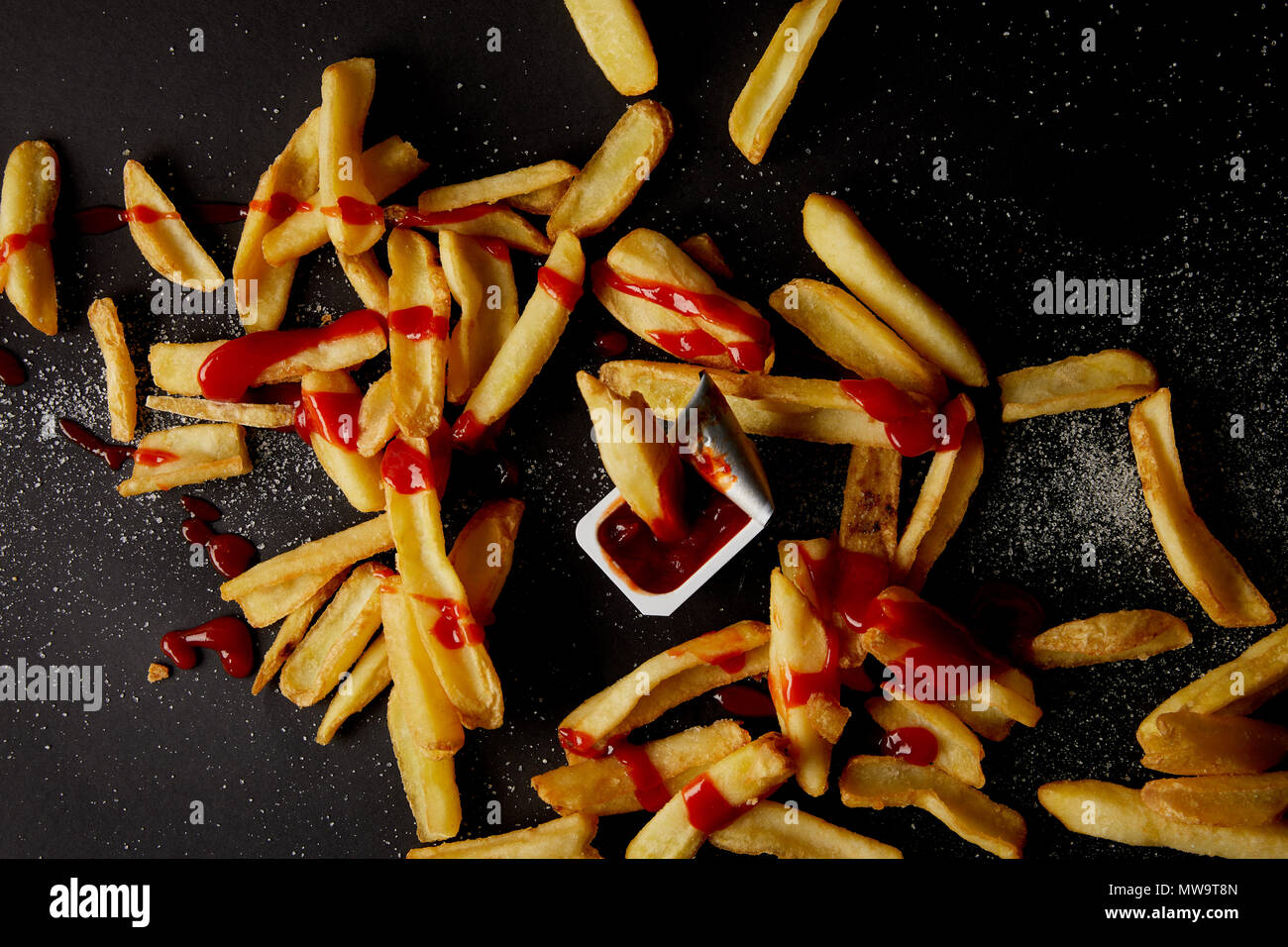 top view of french fries poured with ketchup and spilled with salt on