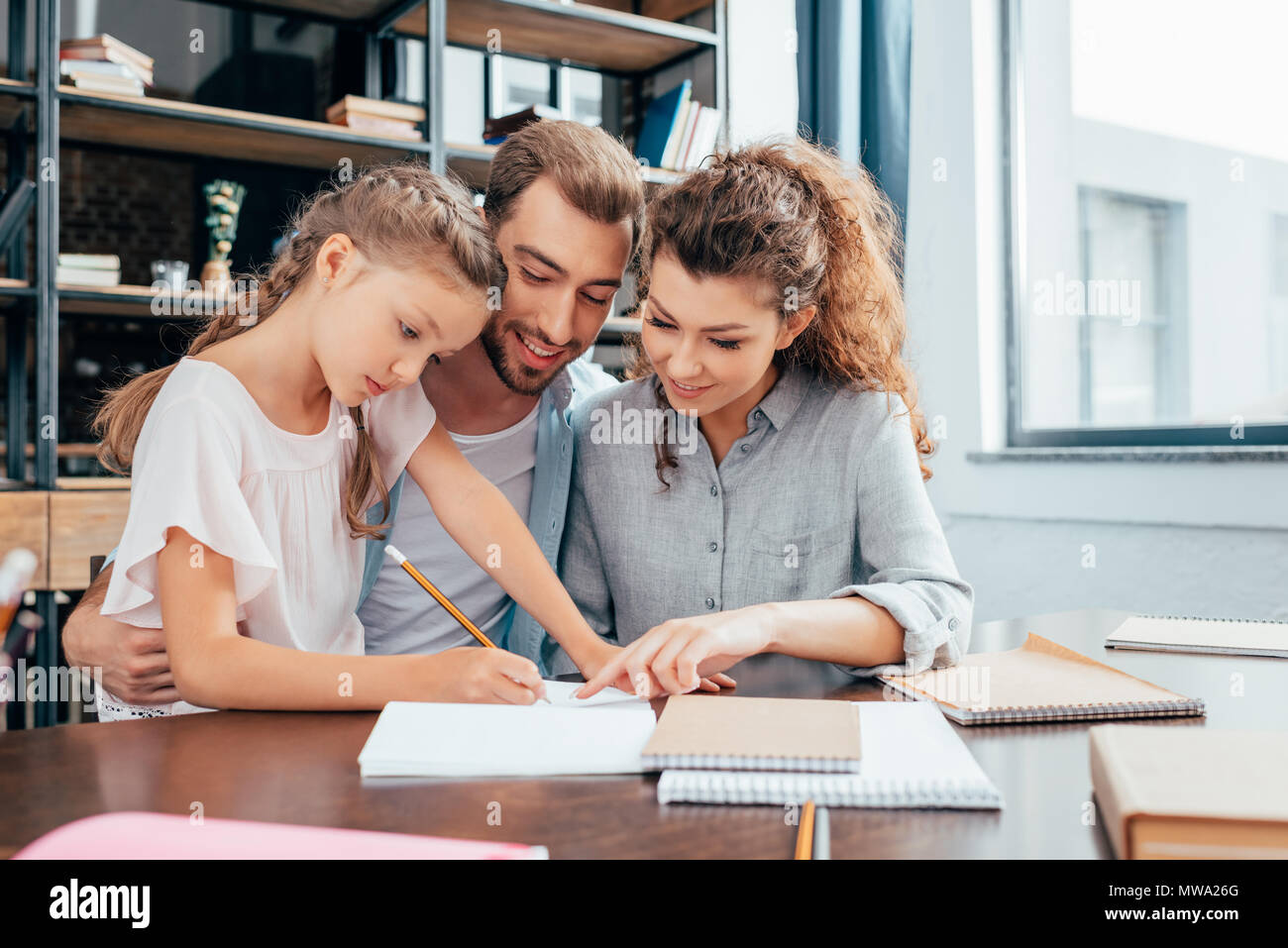 happy beautiful parents doing homework with daughter Stock Photo - Alamy