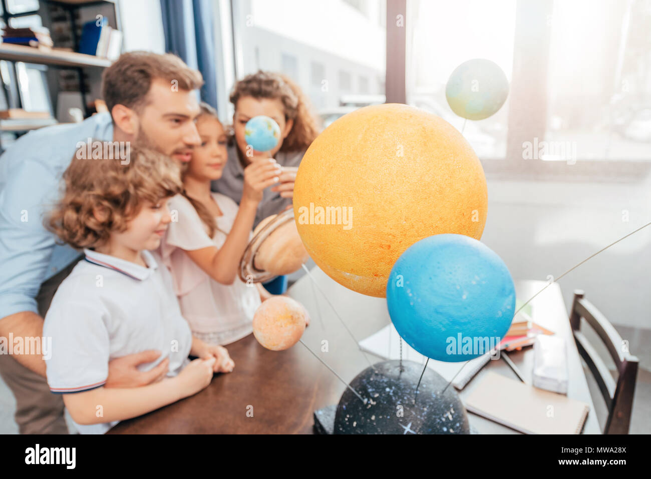Young Happy Family Making Solar System Model For School