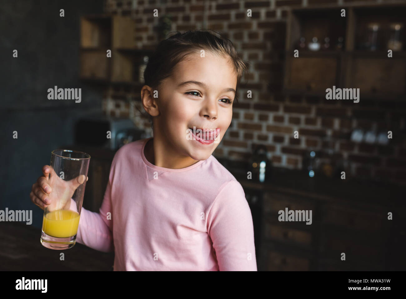 adorable happy child drinking orange juice and licking lips Stock Photo
