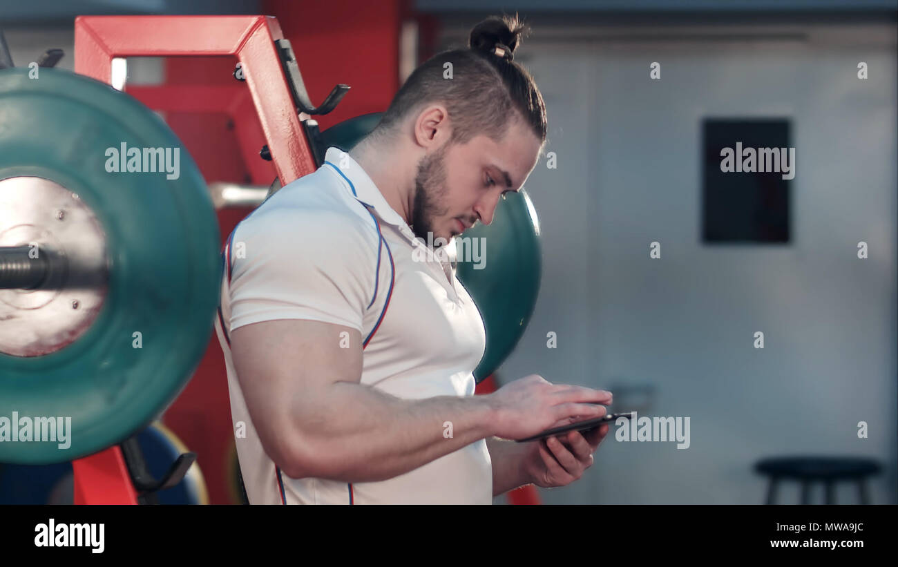 Muscular man using phone in the gym between exercises Stock Photo - Alamy