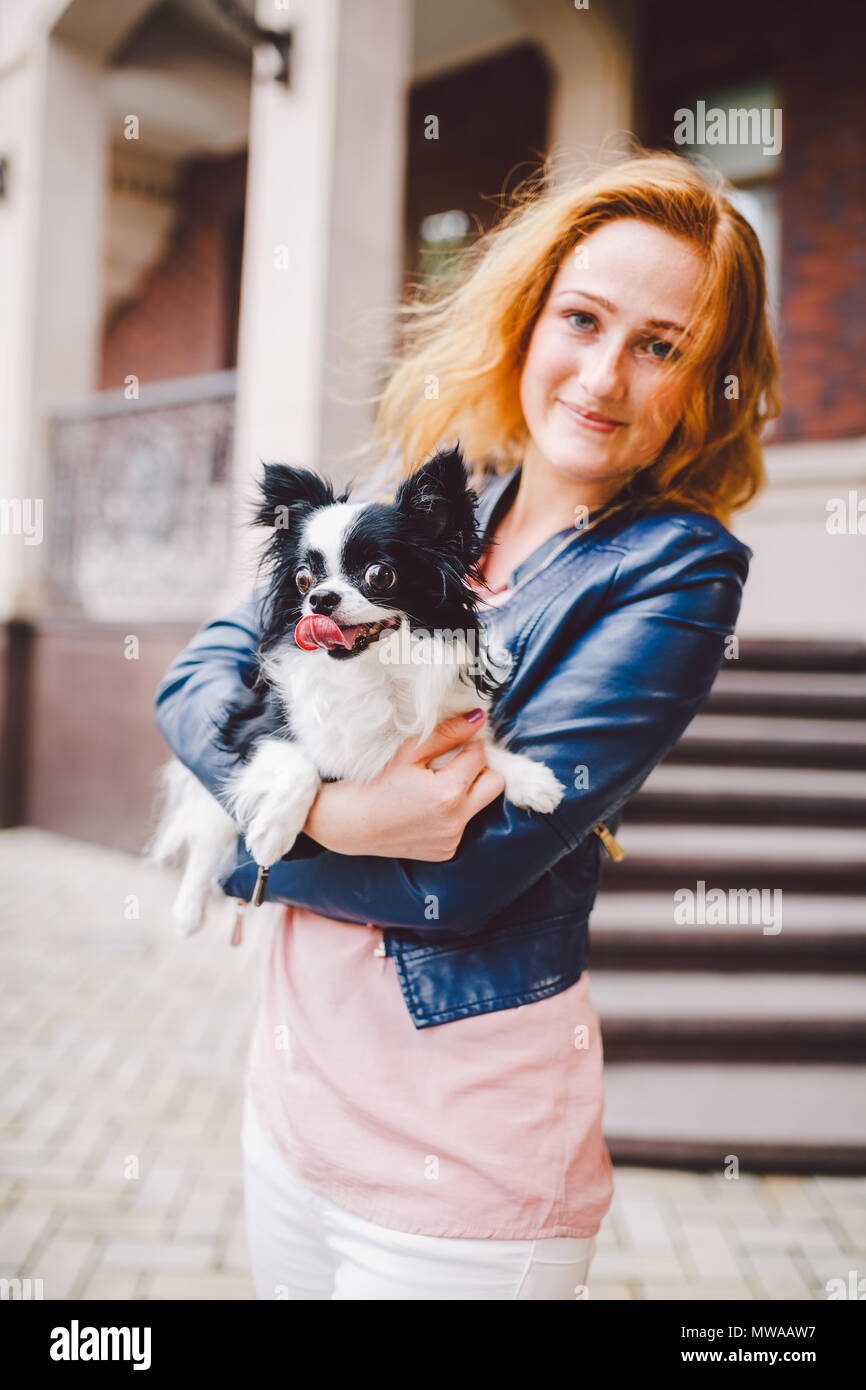 A Beautiful Young Woman With Red Long Hair Is Holding A Small