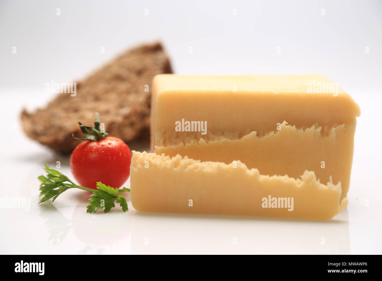 Sliced cheese with a cherry tomato on the side Stock Photo