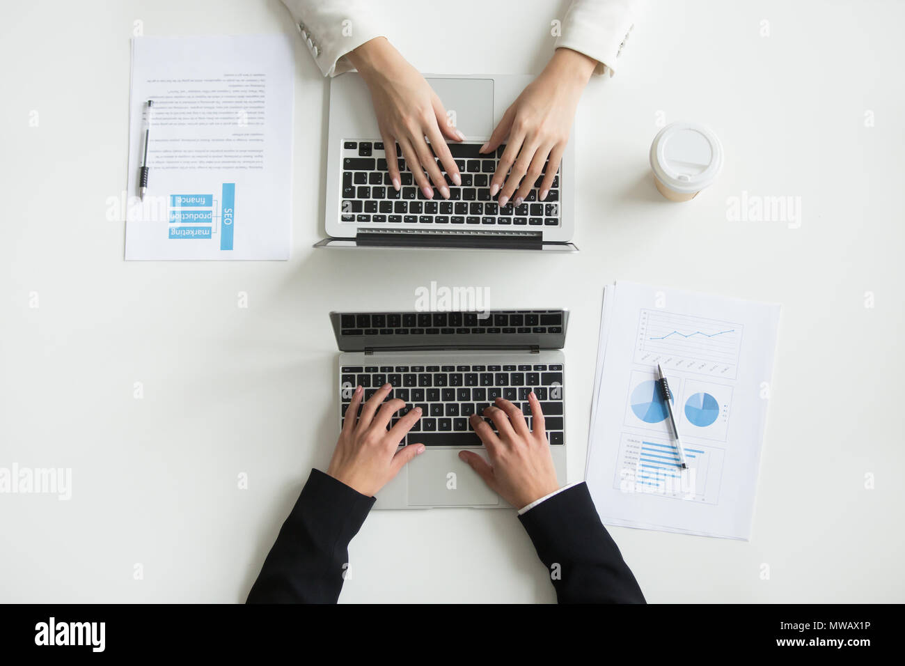 Two office workers typing on laptops, top close up view Stock Photo