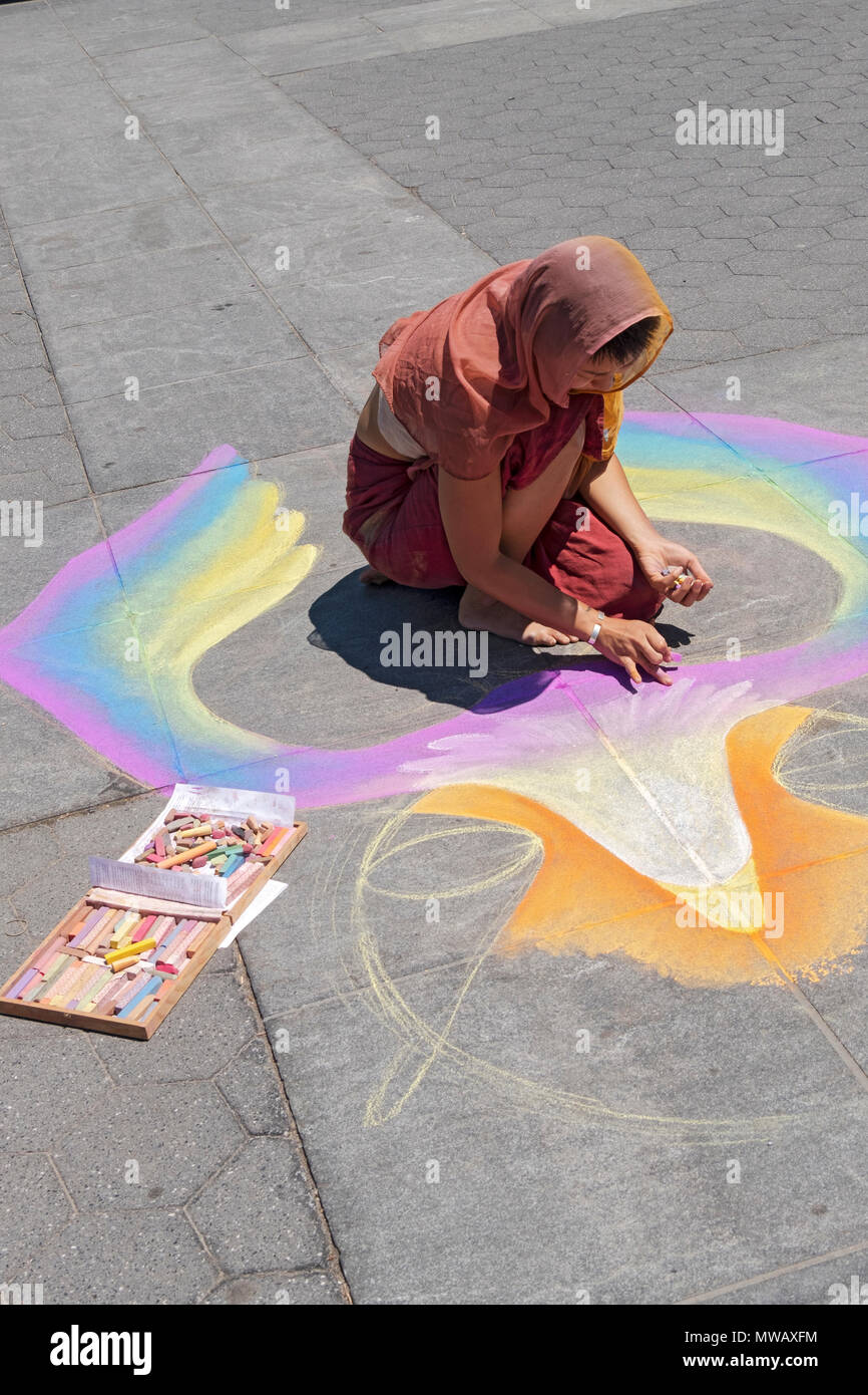 A young Asian woman making a colorful chalk drawing on the ground in Washington Square park in Manhattan, New York City. Stock Photo