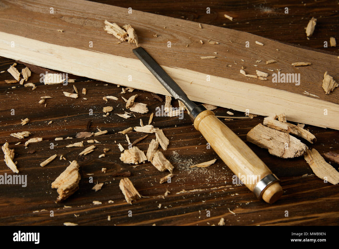 close up view of wooden plank and pieces with chisel on brown table