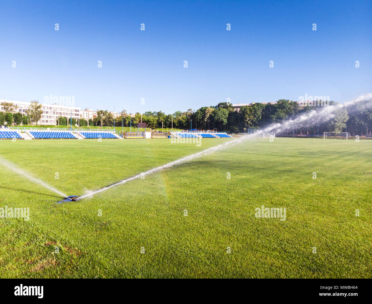 sprinkler watering to green grass field in football / soccer stadium