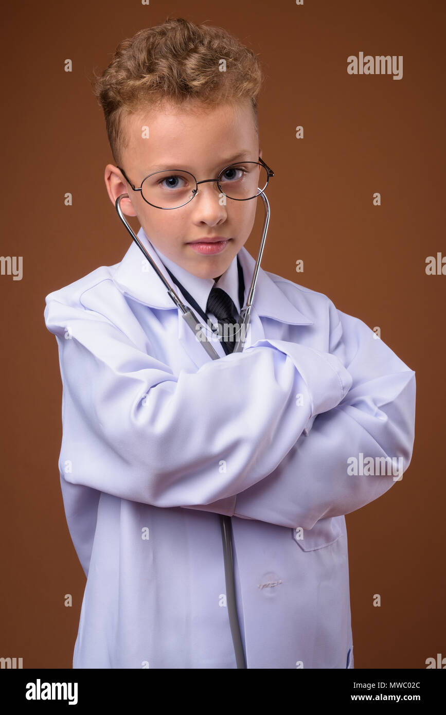 Studio shot of young boy as doctor against brown background Stock Photo