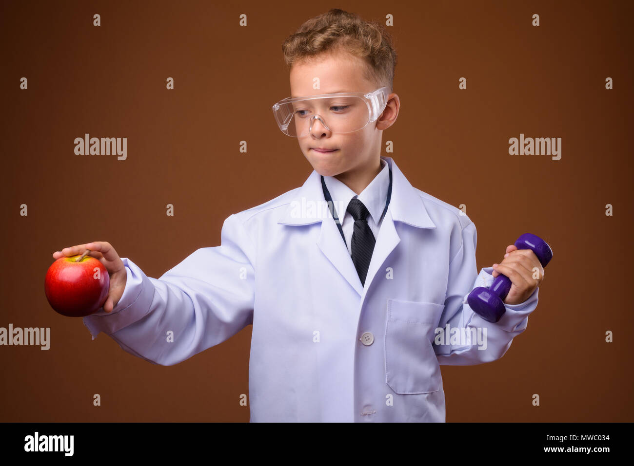 Studio shot of young boy as doctor against brown background Stock Photo