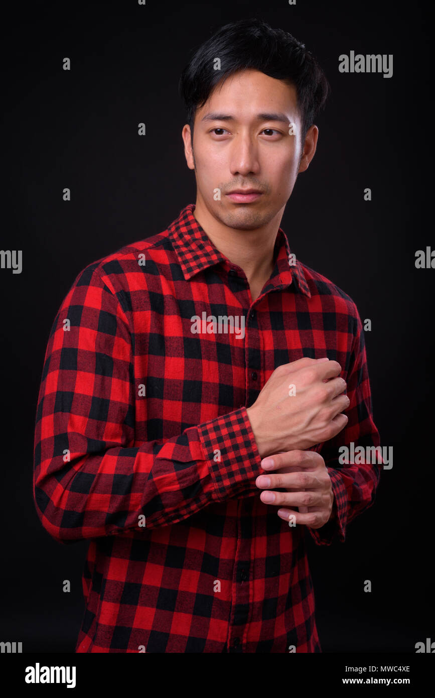 Young handsome Asian man against black background Stock Photo