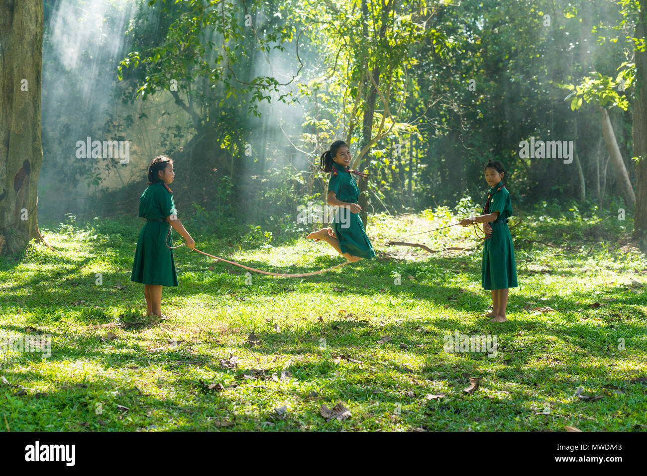 Sakonnakhon, Thailand - July 31, 2016: Three girls in school uniform playing jumping game together on field in rural of Sakonnakhon, Thailand Stock Photo