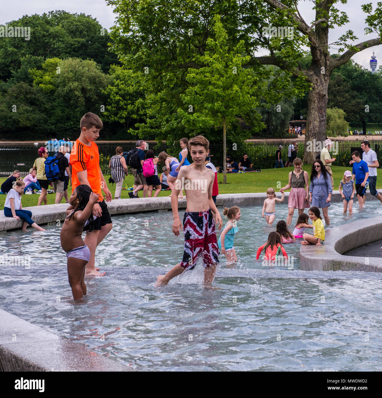 London, UK. 1st Jun, 2018. UK Weather: Cloudy day at Serpentine lake, Hyde Park.  A boy wearing British flag swim trunks smiles at the camera while playing in the water at the Princess Diana Memorial in Hyde Park. Credit: Ernesto Rogata/Alamy Live News. Stock Photo