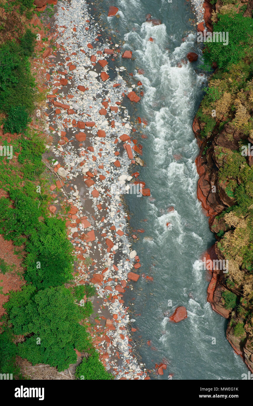 VERTICAL AERIAL VIEW. Large red boulders scattered on the gray riverbed of the Var River. Gorges de Daluis, Guillaumes, Alpes-Maritimes, France. Stock Photo