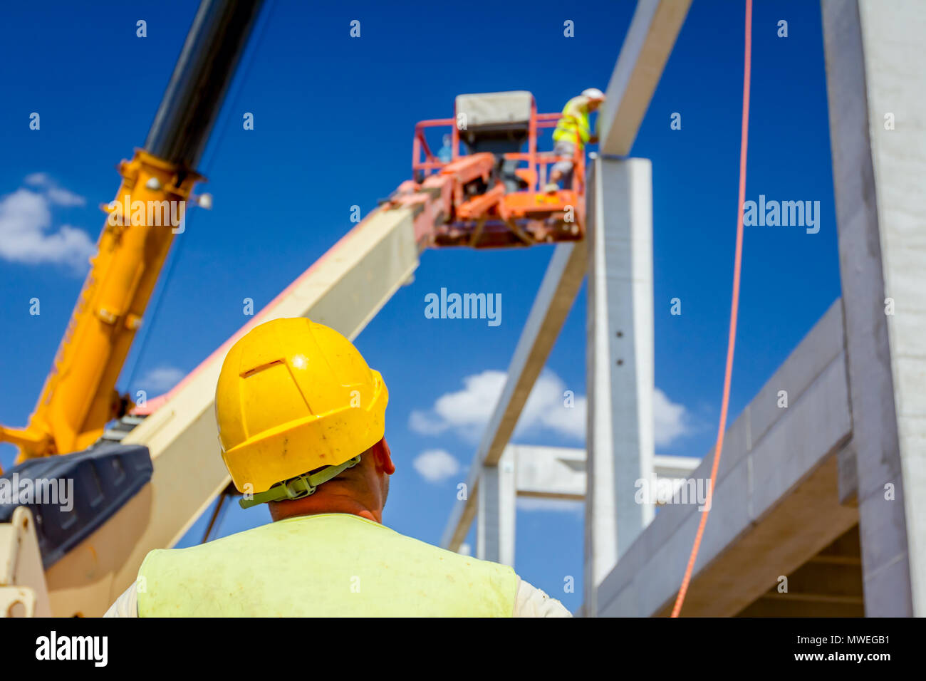 Worker is helping mobile crane with rope to manage concrete joist for ...