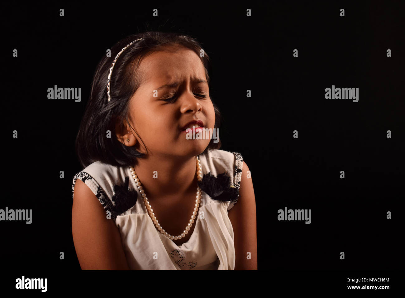 Portrait of little girl with closed eyes in a puzzled expression, Pune Stock Photo
