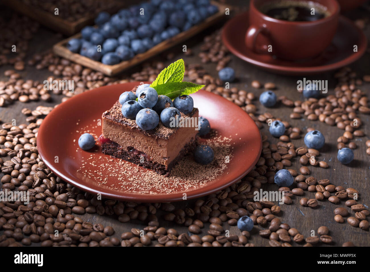 Chocolate cake with blueberries and mint on a brown plate. Chocolate ...