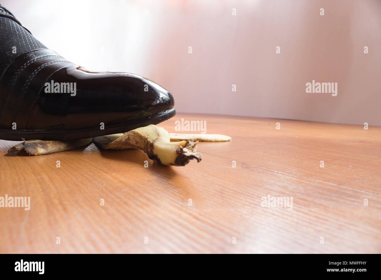 Black patent shoe of young man slipped on a banana peel. Stock Photo