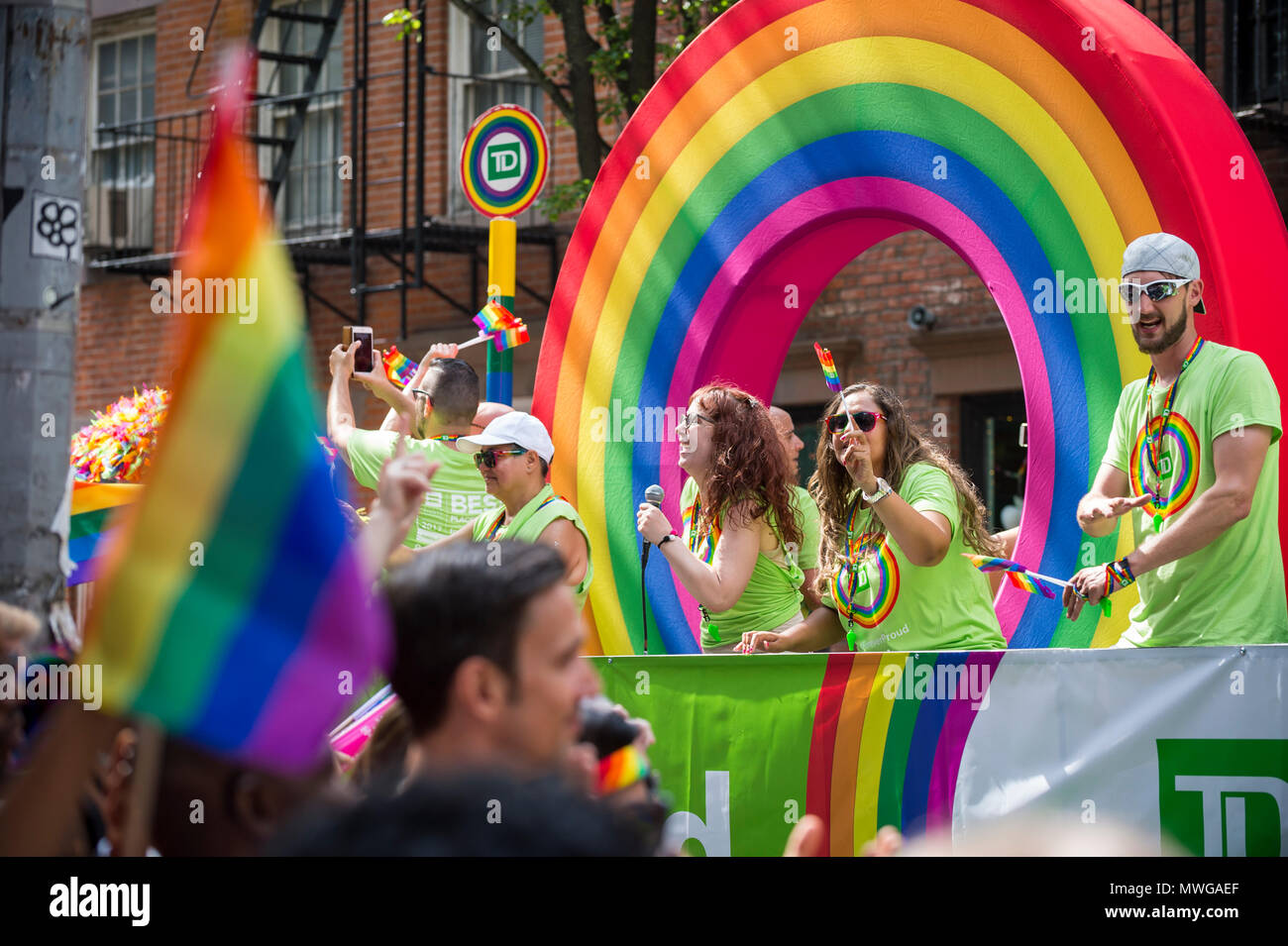NEW YORK CITY - JUNE 25, 2017: Participants wave rainbow flags on a TD Bank float with a rainbow arc in the annual Pride Parade in Greenwich Village Stock Photo
