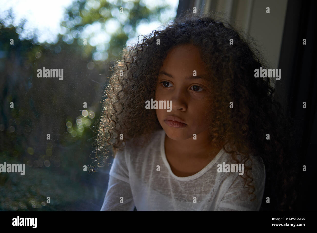 A Young Preteen Mixed Race Girl With Big Curly Hair Looking Out Of